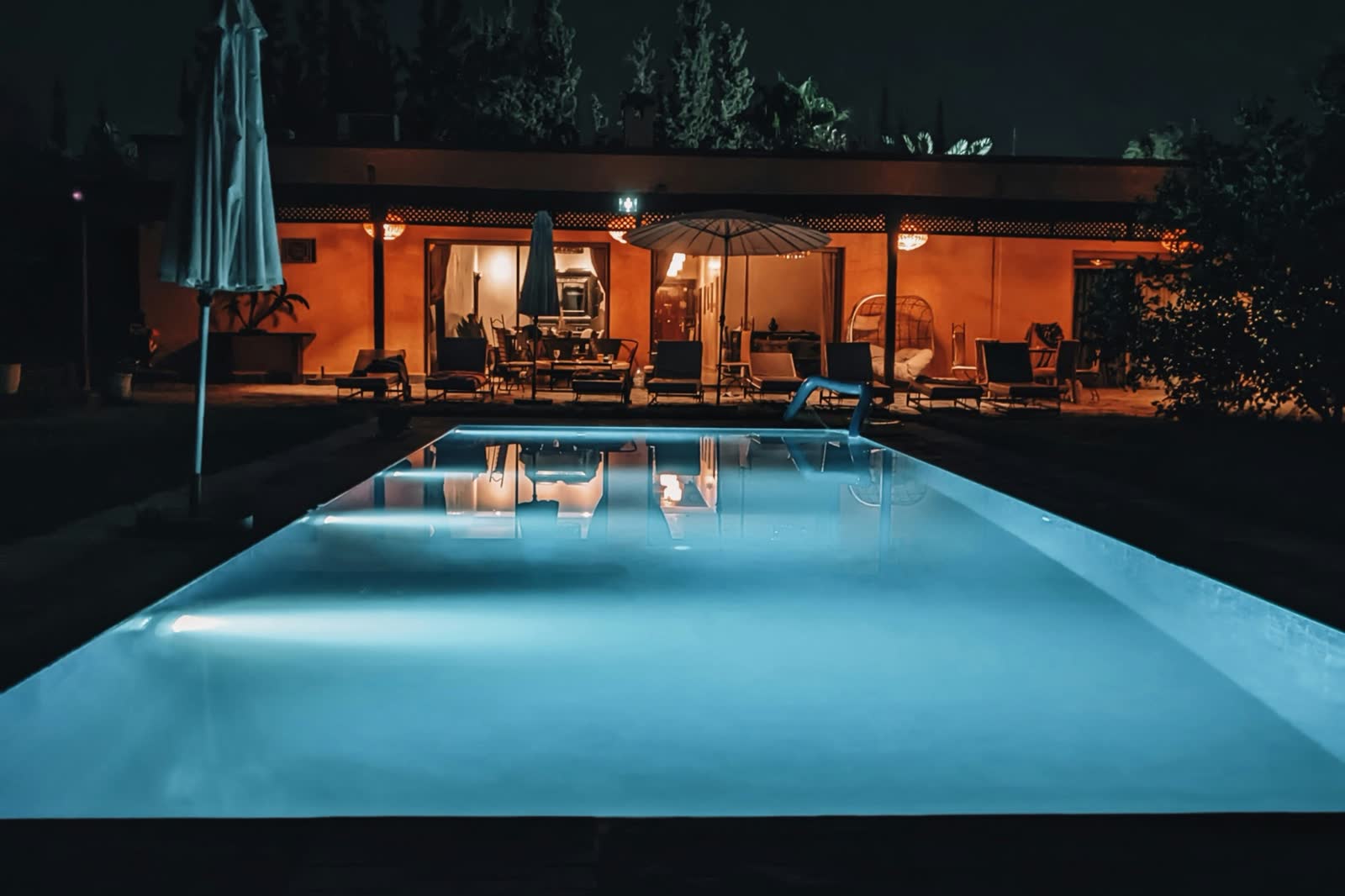 Piscine éclairée de nuit, maison en fond